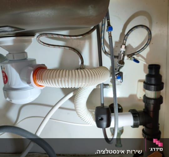 צנרת מתחת לכיור עם מחברים וצינורות גמישים